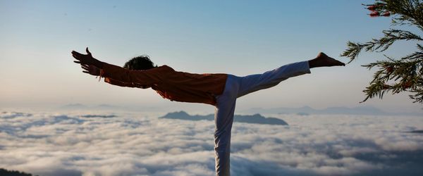 Silhouette of a person in a powerful warrior yoga pose against a window.