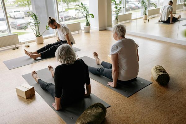 Woman performing a fluid yoga sequence in a bright, sunlit studio.